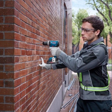 Operario utilizando el taladro percutor Bosch GSB 18V-65 para perforar una pared